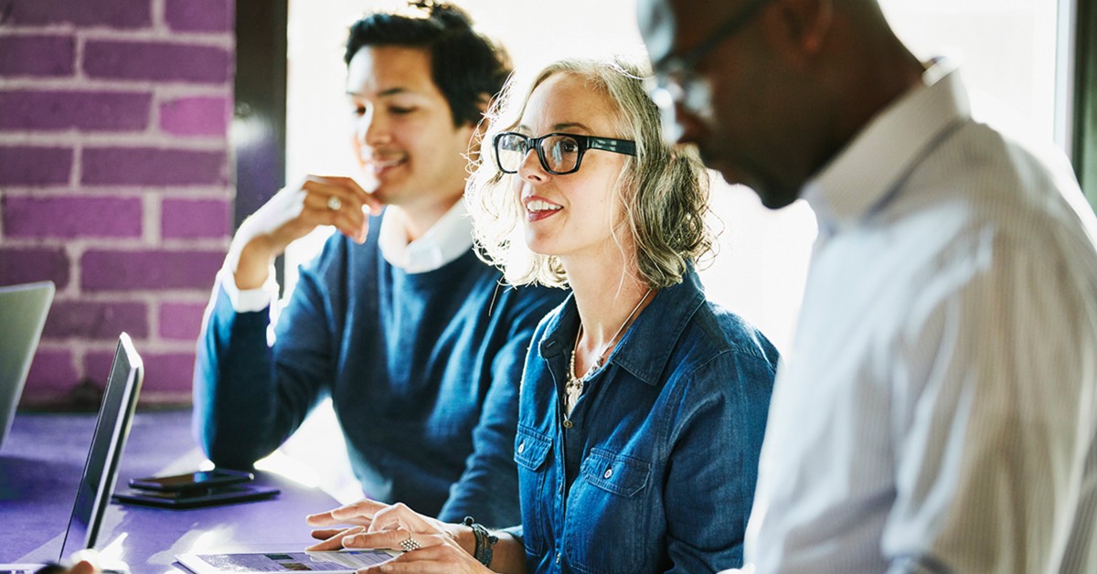 Photo of three people collaborating around a computer